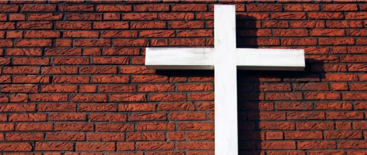 Weißes Kreuz vor Backsteinmauer